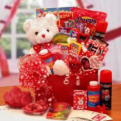 a white teddy bear sitting in a red basket filled with valentine's day treats