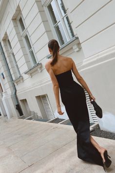 a woman in a black dress walking down the street