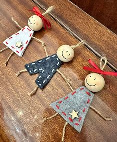 three small wooden dolls are hanging on a table with twine and ribbons around them