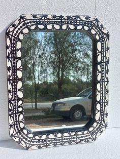 a car is seen in the reflection of a mirror that has been painted black and white