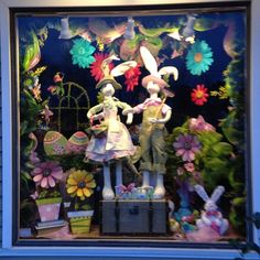 a window display with rabbits and flowers in the front, behind which is an image of two people holding hands