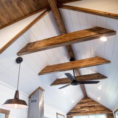 the ceiling fan is hanging from the wooden beams in the room with white walls and wood flooring