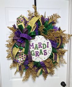 a wreath that says mardi gras is hanging on the front door with purple and green decorations