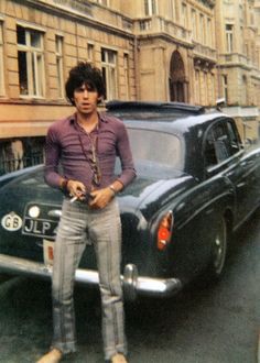 a man standing in front of a black car