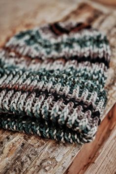 a knitted hat sitting on top of a wooden table next to a piece of wood