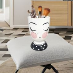 a cup with makeup brushes sticking out of it sitting on top of a chair in a room