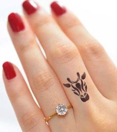 a woman's hand with a giraffe tattoo on her finger and a diamond ring