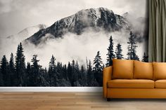 a couch sitting in front of a window with a mountain mural on it's wall