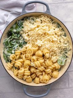 a pot filled with pasta and spinach on top of a table