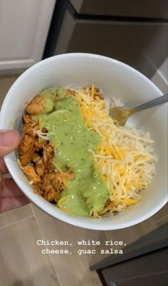 a person holding a white bowl filled with chicken, cheese and guacamole