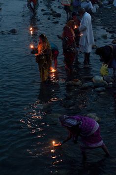 many people are standing in the water with candles