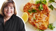 a woman standing in front of a plate of food with lemon wedges on it