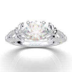 a white gold ring with an intricate design and round brilliant diamond center stone in the middle