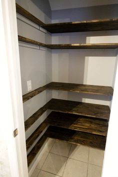 an empty walk in closet with wooden shelves