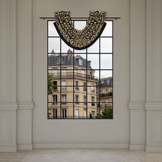 an empty room with a window that has curtains on the windowsill and a building in the background