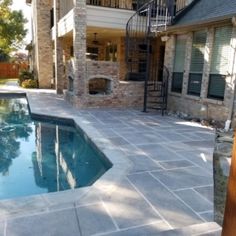 a pool in the middle of a backyard with stairs leading up to an upper level balcony