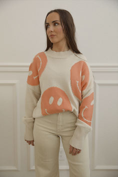 cream knit sweater with orange smiley faces Oversized Fun Fall Sweater, Oversized Fun Sweater For Fall, Playful Crew Neck Fall Sweater, Playful Crew Neck Sweater For Fall, Oversized Playful Sweater For Fall, Playful Oversized Sweater For Fall, Trendy Relaxed Fit Sweatshirt With Smiley Face, Fall Crew Neck Sweatshirt With Smiley Face, Trendy Long Sleeve Sweatshirt With Smiley Face