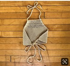 a crocheted apron hanging on a wooden wall with white string attached to it