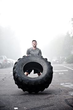 a man standing on top of a giant tire