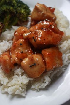 a white plate topped with rice and chicken covered in sauce next to broccoli