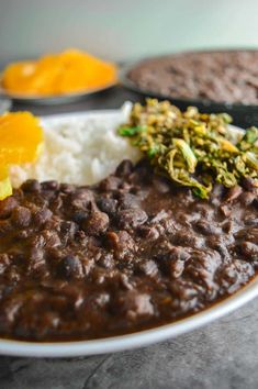 a white plate topped with beans and rice next to other foods on top of a table