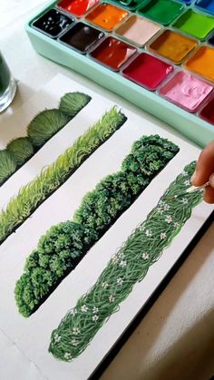 a person is painting some plants with watercolors