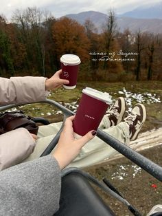 a woman holding a cup of coffee in her hand while sitting on top of a vehicle