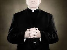 an older man in a priest's outfit standing with his hands folded over his chest