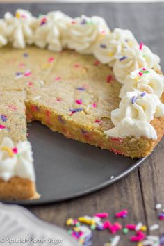 a cake with white frosting and sprinkles on a plate next to a fork