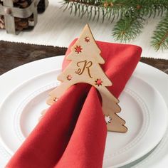 a wooden christmas tree decoration on top of a red napkin with a monogrammed letter