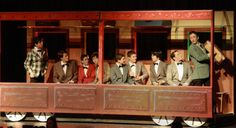 a group of young men standing on top of a wooden train car in front of a crowd