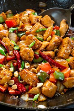 chicken stir fry in a wok with vegetables and nuts on the side, ready to be eaten