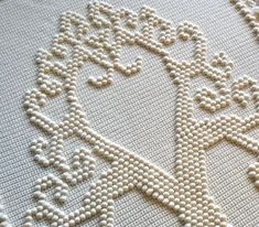 a close up view of a cross stitch pattern on a rug with beads and crochet