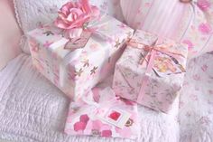 two wrapped presents sitting on top of a bed next to pillows and a pillow with a pink flower