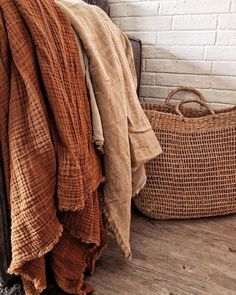 a basket and blanket on the floor next to a brick wall