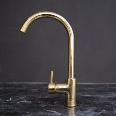 a gold faucet on a marble countertop with black walls in the background