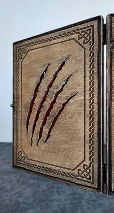 an open wooden box with designs on the front and back sides, showing red streaks