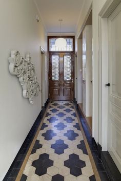 a long hallway with black and white tiles on the floor next to a wooden door