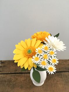 a white vase filled with yellow and white flowers