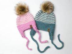 two knitted hats with pom - poms on them