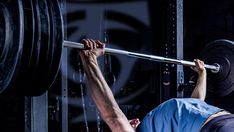 a man lifting a barbell in a gym with his hands on the back of him