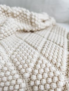 a white crocheted blanket laying on top of a bed