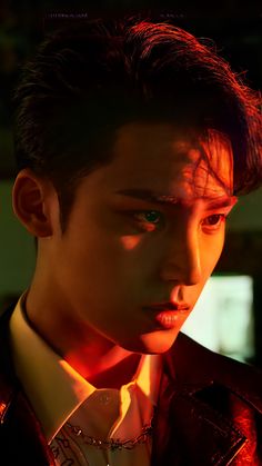 a young man in a suit and tie looking at the camera with red light shining on his face