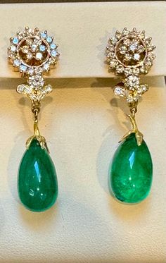 GIA Certified 28 Ct Emerald Cabochon & Diamond Drops Hanging Earrings 14 KYG This exquisite pair of earrings are beautifully crafted with 14 karat yellow gold weighing 14 grams Two fine Cabochon Emerald weighing approximately 14 carats each totaling approximately 28 carats of Emerald Drops. Finest color and quality. There are brilliant cut diamonds which are making a circular surround around a 7 piece diamond flower. Total diamond weight approximately 2 ct Origin Zambia GIA Certificate # 2239113214 Color: Deep Green, Transparent extreme Fine Color Quality Earring has a post and Omega backs. Very comfortably sits on the earlobe . FOLLOW MonalisaJewelry Inc. storefront to view the latest collection. We encourage you to take a look at all the pictures provided for this item. As it can be diff Elegant Drop Earrings With Cabochon, Formal Cabochon Earrings In Fine Jewelry Style, Formal Cabochon Fine Jewelry Earrings, Exquisite Cabochon Earrings For Formal Occasions, Oval Cabochon Earrings For Evening, Fine Jewelry Drop Earrings With Cabochon, Formal Dangle Earrings With Cabochon, Exquisite Formal Cabochon Earrings, Diamond Cabochon Earrings For Anniversary