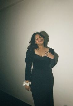 a woman in a black dress posing for the camera with her arms around her chest