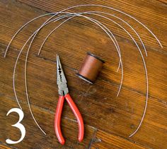 a pair of scissors and some wire on a wooden floor with the number three in front of it