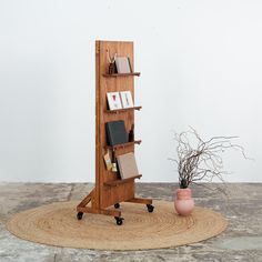 a wooden book shelf sitting on top of a rug next to a potted plant