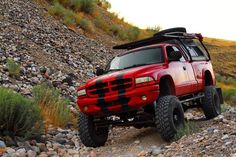 a red truck driving down a rocky road