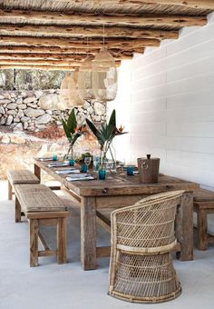 a wooden table sitting under a roof covered in plants