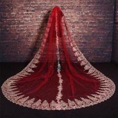 a red bridal veil with white lace on it and a brick wall in the background